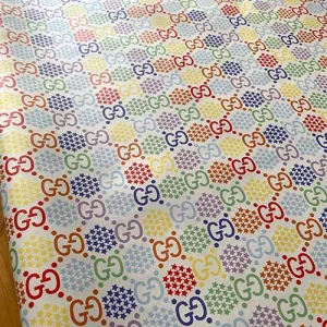 white gucci leather fabric which has multicolored patterns on